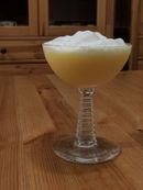 A creamy-looking yellow cocktail topped with a layer of white foam