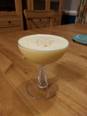 A creamy-looking egg sour, filling a small coupe glass to the brim