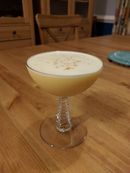 A creamy-looking egg sour, filling a small coupe glass to the brim