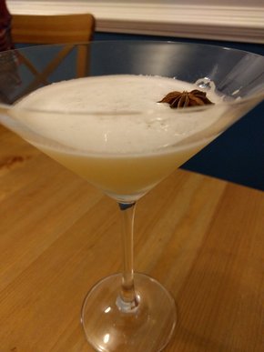 Closeup photo of the cocktail in a martini glass with a star anise floating on top