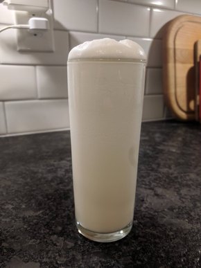 A white foamy drink in a tall narrow glass