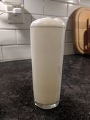 A white foamy drink in a tall narrow glass