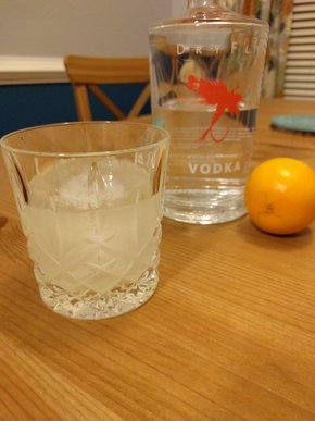 A crystal glass with the cocktail in front of a bottle of Dry Fly vodka and a meyer lemon